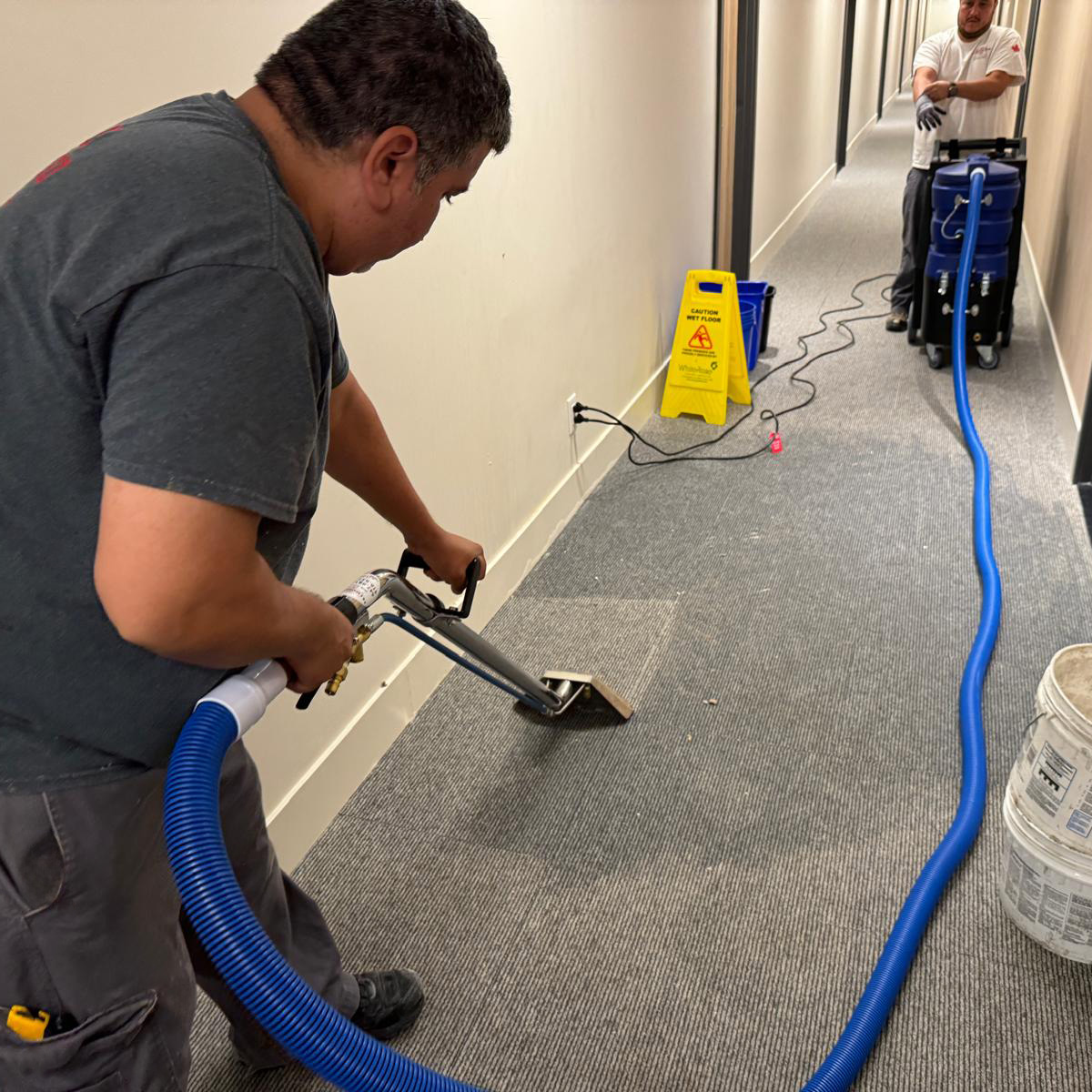An E & E Restorations employee extracting the water from a condo hallway
